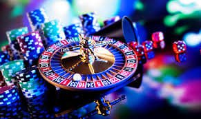 Meja Baccarat live casino dengan kartu terbuka dan chip taruhan di atas meja hijau studio profesional
